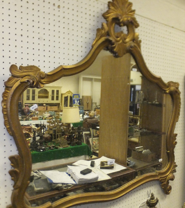 A shaped wall mirror in gilt foliate moulded frame