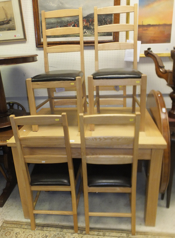 A modern light oak dining table and six ladder back chairs with black upholstered seats