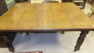 A Victorian oak extending dining table on turned and reeded tapering supports to castors