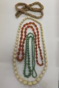 An early 20th century ivory bead necklace, an orange agate necklace, a green glass bead necklace,