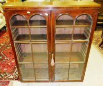 A 19th century mahogany bookcase with two glazed doors and arched decoration, opening to reveal