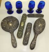 Three various embossed sterling silver backed dressing table items to include two brushes and a