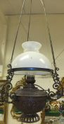 A brass bodied ceiling light fitting with opaque glass shade, clear glass chimney and brass embossed