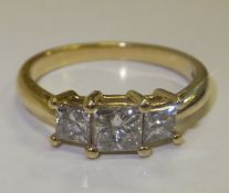An 18 carat gold three stone diamond ring, the stones of princess cut, approx 0.6 carats total