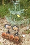 A painted wirework three tier plant stand, two shell decorated bird baths, four terracotta pots, and