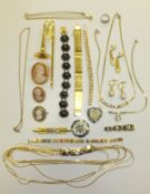 A box of assorted jewellery to include cameo style brooches, a model trombone, various necklaces,