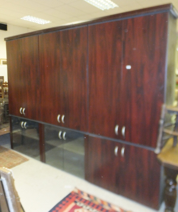A large mahogany effect bookcase cabinet with three pairs of doors enclosing shelves above a further