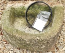 A reconstituted stone D-shaped trough and a wrought iron wheel ornament