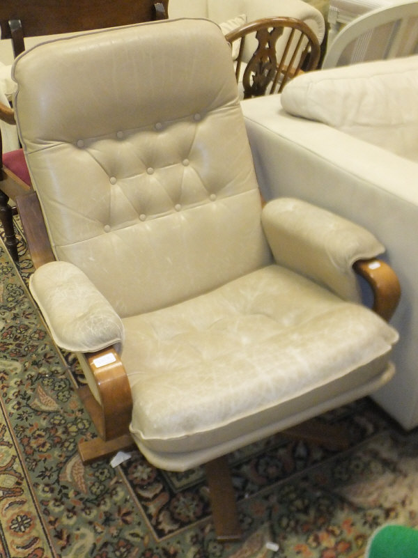 A modern button back swivel armchair with beige upholstery
