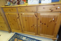 A modern pine sideboard of three drawers over three cupboard doors, together with a pine TV