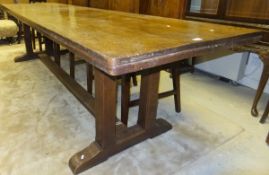 An Arts and Crafts oak refectory style dining table, the plank top on chamfered twin trestle end