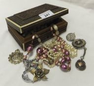 A carved Indian jewellery box containing assorted costume jewellery to include a locket stamped "