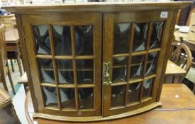 An early 20th Century oak bow fronted glazed hanging display cabinet