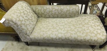 An upholstered chaise longue on turned and ringed legs to brass castors