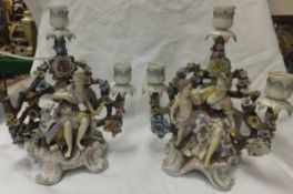A pair of Sitzendorf porcelain floral encrusted three branch candelabra decorated with seated