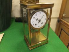 A brass cased four glass mantel clock with circular enamel dial and Arabic numerals
