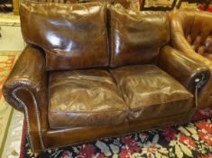 A brown leather scroll arm two seat sofa with brass stud decoration