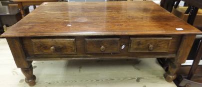 A rectangular teak coffee table with three short drawers either side of the frieze, standing on
