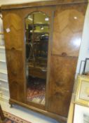An Art Deco style walnut veneered single door wardrobe with shaped bevel edged glass door