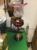 A Victorian brass column oil lamp with cranberry reservoir and cranberry tinged handkerchief shade