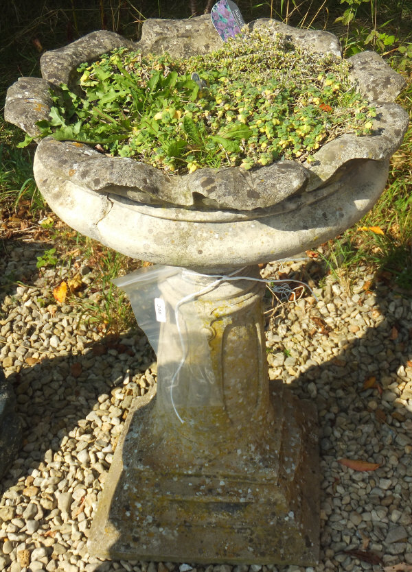 A reconstituted stone garden urn on pedestal stand