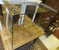 A clear glass desk together with a cream painted side table with two short frieze drawers