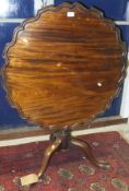 A mahogany tea table in the George III taste, the circular snap top with pie crust edge on a