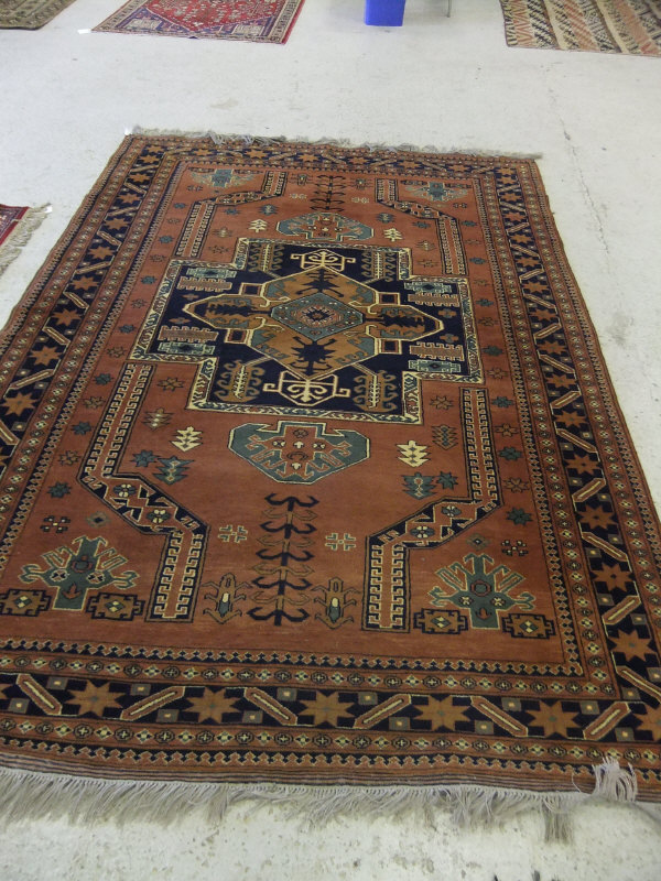 An Afghan rug, the central terracotta, blue and cream geometric shaped lozenge on a terracotta