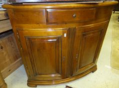 A modern bow fronted corner cabinet with single drawer above two cupboard doors