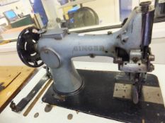 A galvanised industrial sized Singer sewing machine raised on grey painted metal base with