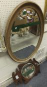 An oak framed oval wall mirror with bevelled glass, together with a further wall mirror