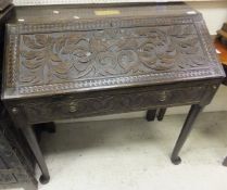 An oak bureau with carved Victorian Gothic style decoration, the shallow fall enclosing a basic