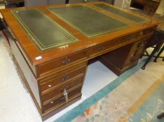 A modern mahogany partner's desk with tooled and gilded leather insert top over three frieze drawers