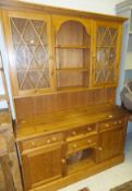 A modern pine dresser, the top with central plate rack flanked by two glazed doors over a base of