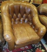 A brown leather tub armchair with button back and arms