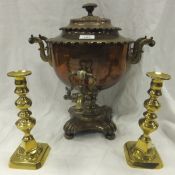 A Victorian copper tea urn and a pair of brass candlesticks