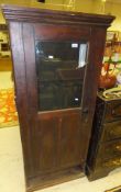A stained pine cabinet with glazed panelled door