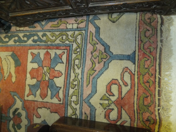 A Turkish carpet, the centre field with stylised cream, blue and red motifs on a pale red ground,