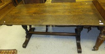 An oak trestle end table in the 17th Century manner, the planked top raised on two cup and cover