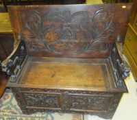 A carved oak monk's bench with foliate carved decoration and raised back on lion supports to a