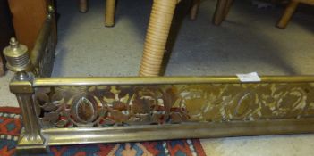 A brass fender with pierced foliate and scrolling decoration