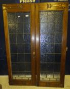A pair of oak framed leaded glazed doors with Arts & Crafts brass mounts, a carved wooden panel "