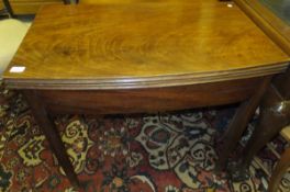 An early 19th century mahogany tea table with bow front, with foldover top to plain deep frieze on