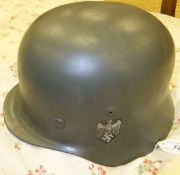 A World War II German Heer helmet with black, white and red decal to one side, and eagle carrying