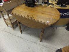 A pine oval drop leaf dining table on reeded legs