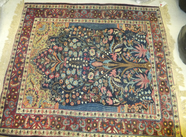 A Persian prayer rug with tree of life decoration, set on a blue ground within a stepped cream and