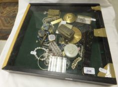 A small glazed display case containing a collection of costume jewellery, powder compacts, etc