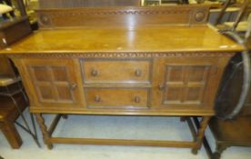 An early 20th Century oak sideboard, the rectangular top with carved upstand over two drawers