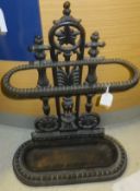 A cast iron umbrella stand with shaped and pierced back