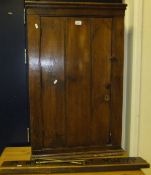 A stained and waxed pine wall cupboard, the panelled door opening to reveal three shelves